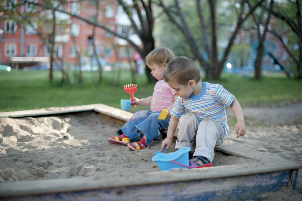 Two cute little children brother and sister playing in a sandbox